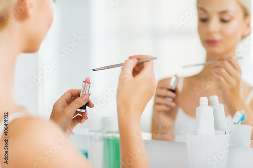 woman with lipstick and make up brush at bathroom