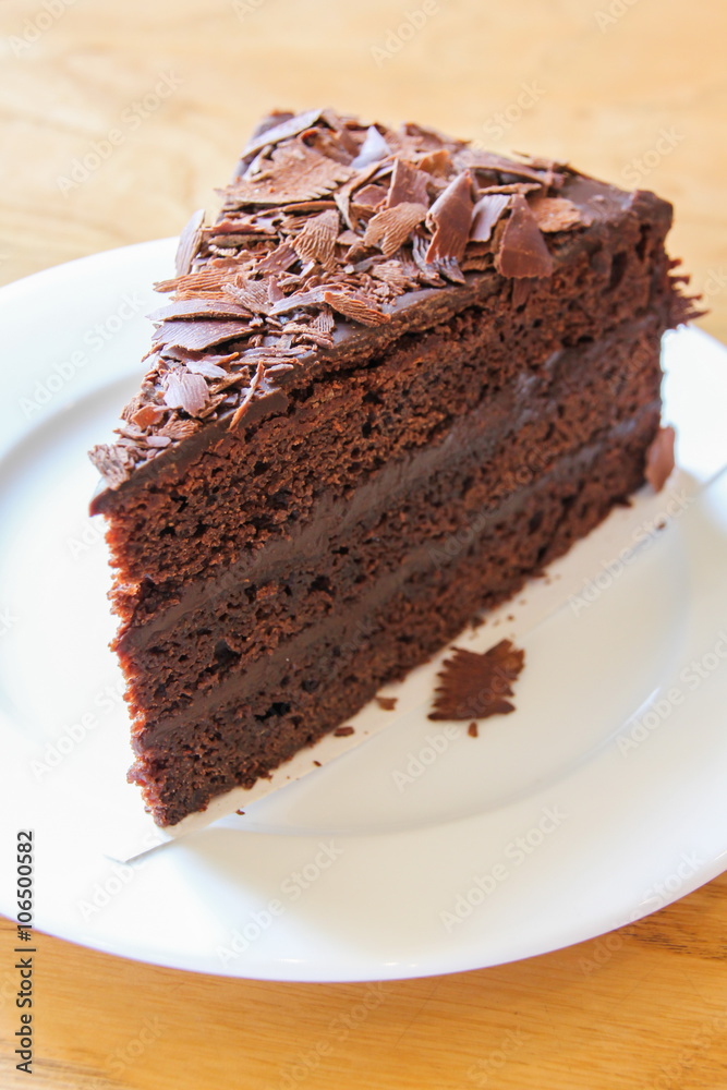 A piece of soft chocolate cake on white plate.