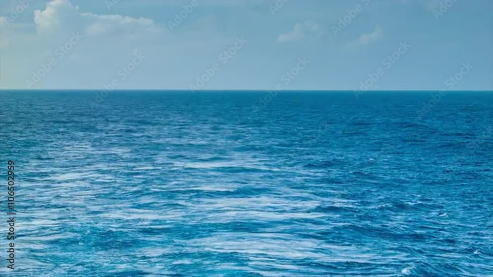 A Wake From a Ship at Sea with Blue Ocean Water, a Horizon, Blue Sky and Clouds A Wake From a Ship at Sea with Blue Ocean Water, a Horizon, Blue Sky and Clouds