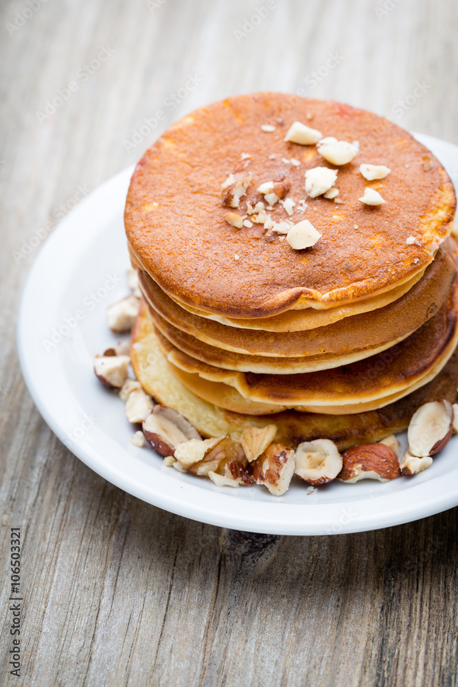 Stack of homemade pancakes with honey on wooden background.