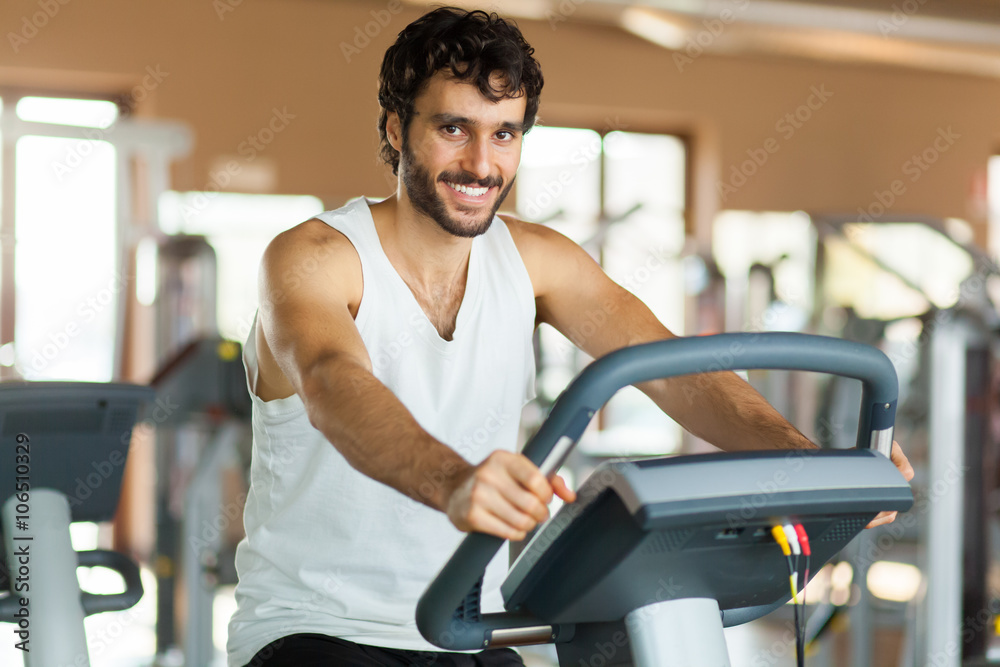 Man in the gym, exercising his legs doing cardio training on bicycle Man in the gym, exercising his legs doing cardio training on bicycle