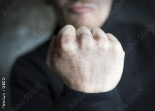 Male threatening gesture, fist on dark background