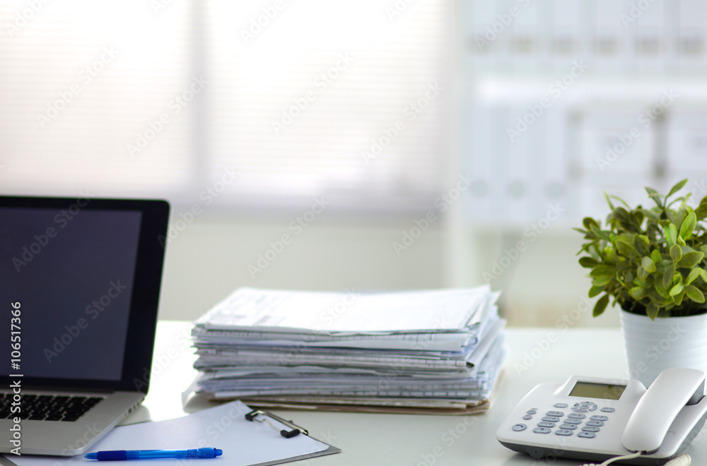 Laptop with stack of folders on table on white background Laptop with stack of folders on table on white background