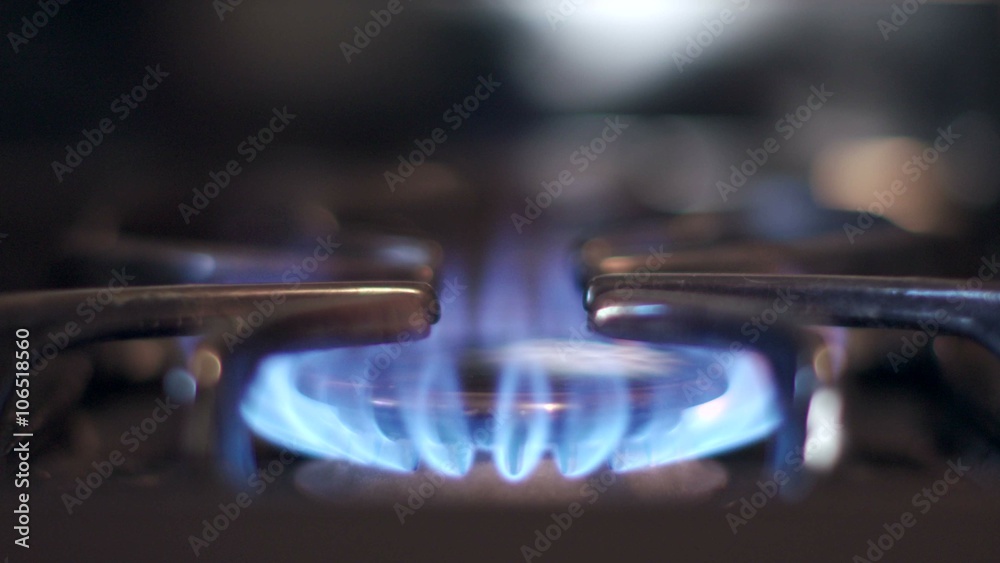Stove top burner igniting into a blue cooking flame in 4K UHD. 