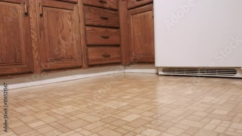camera moves left and right on the corner of an old yellow kitchen. Focus on yellow linoleum floor in foreground