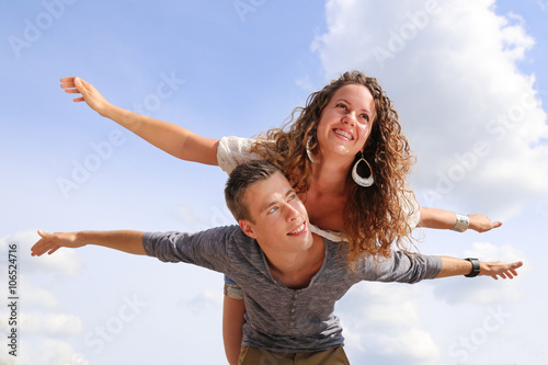 happy young couple having piggyback under blue sky