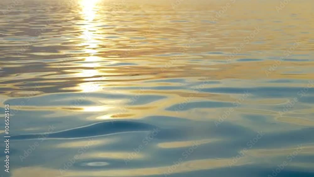 Slow motion of sea water with slight ripple sparkling in light of sunset. Water surface background with golden path of evening sun reflection