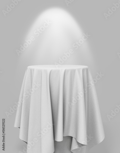white cloth on a round pedestal on a gray background with illumi