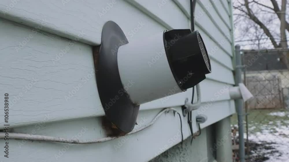 a tankless water heater vent sticks out of the side of a house. The camera pushes in and pulls back at an angle