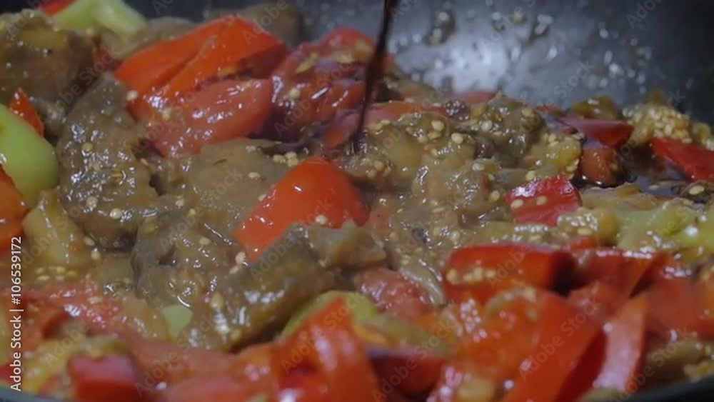 Slow motion close-up shot of pouring soy sauce into the frying-pan with stewed vegetables. Cooking vegetarian dish Slow motion close-up shot of pouring soy sauce into the frying-pan with stewed vegetables. Cooking vegetarian dish