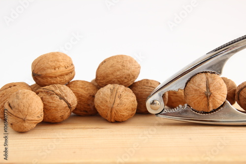 English or Persian walnuts and metal nutcracker on a wooden background. photo