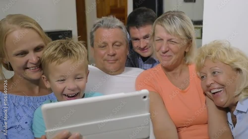 Slow motion of big family watching film on tablet computer at home. It making them smile and laugh Slow motion of big family watching film on tablet computer at home. It making them smile and laugh