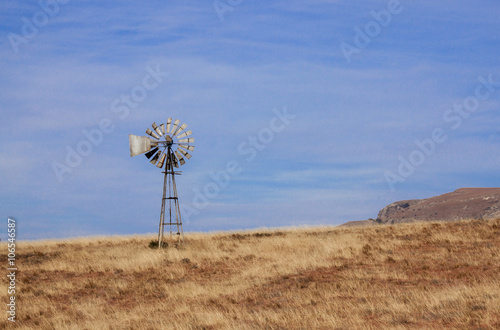 Lone Windmill Against Blue Sky in Dry Grassland Field
