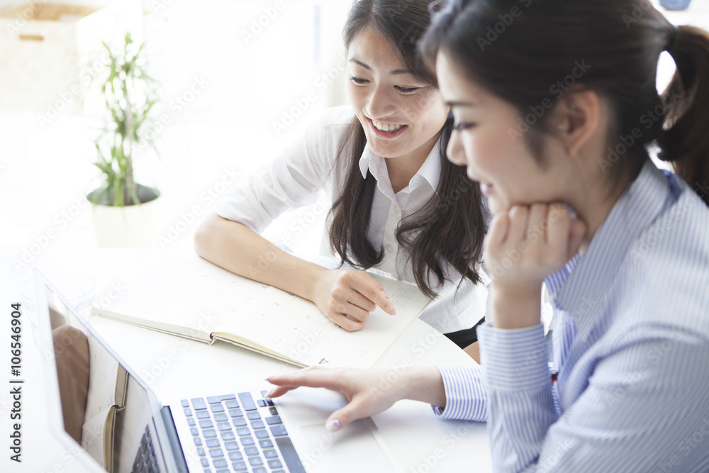 Two business women looking at a laptop together Two business women looking at a laptop together