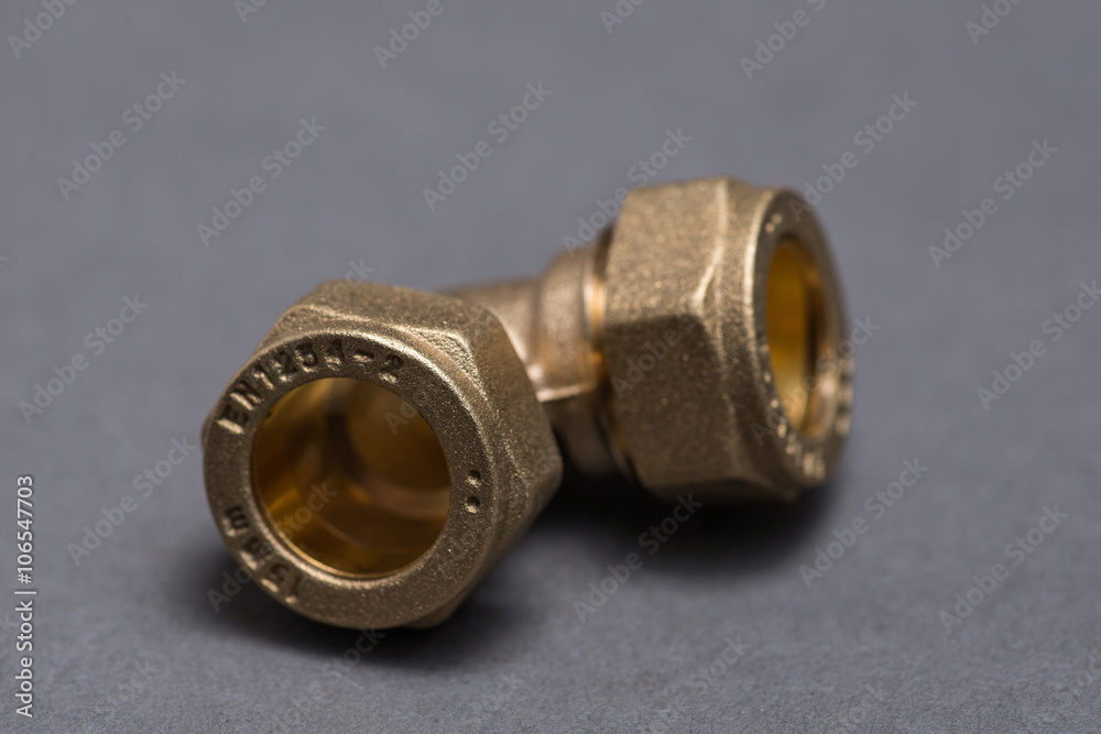Brass plumbing compression fittings on grey table Brass plumbing compression fittings on grey table
