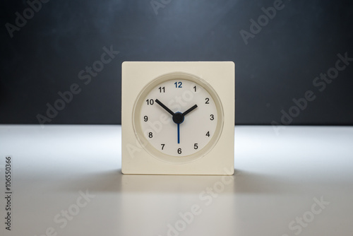 white clock on a white table against the background of black and white board. Black classic glasses