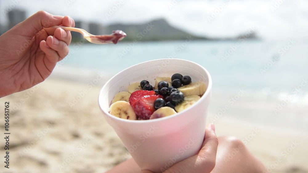 Acai bowl girl eating healthy food on beach. Woman enjoying acai