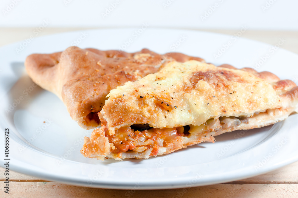 pizza puff on white plate over wooden background