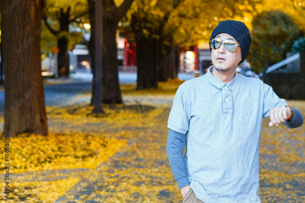 An asian man in a polo t-shirt walks on a street An asian man in a polo t-shirt walks on a street