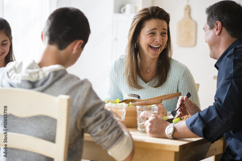 Caucasian family laughing and eating at table Caucasian family laughing and eating at table