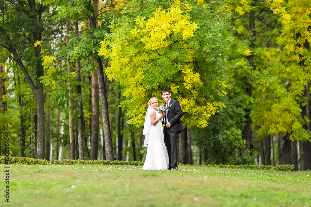 couple in wedding attire with a bouquet of flowers, bride and groom outdoors couple in wedding attire with a bouquet of flowers, bride and groom outdoors