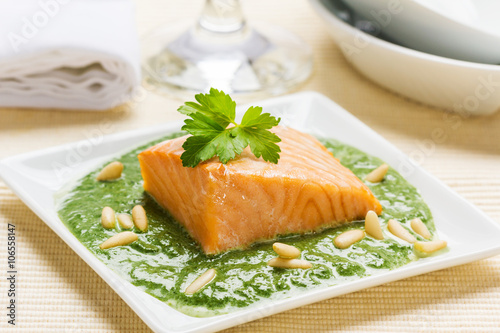 Steamed salmon in a spinach cream sauce with pine seeds.