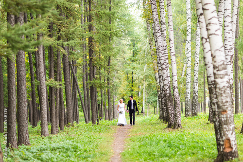 couple in wedding attire with a bouquet of flowers, bride and groom outdoors © satura_