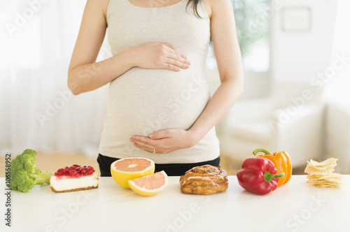 Health and unhealthy foods in front of pregnant Japanese woman  photo