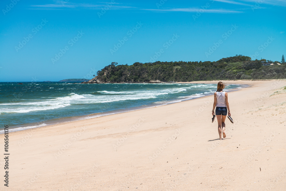 Woman walking along a completely deserted beach strip on the eastern coast of Australia.