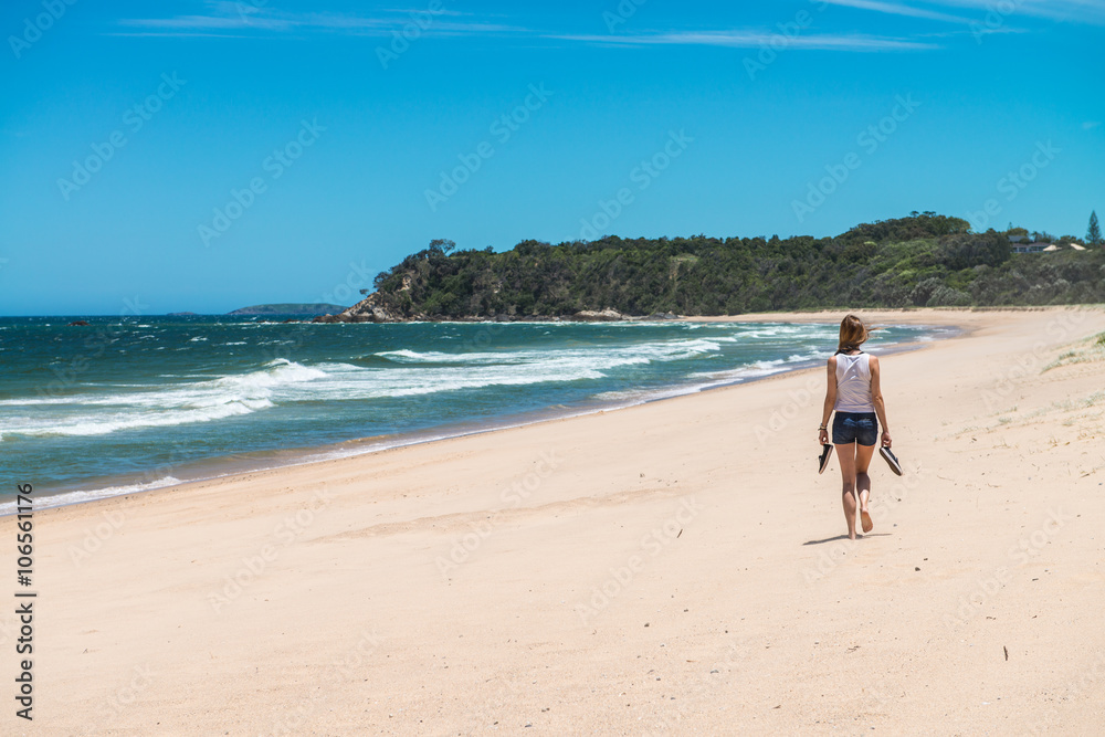 Woman walking along a completely deserted beach strip on the eastern coast of Australia. Woman walking along a completely deserted beach strip on the eastern coast of Australia.