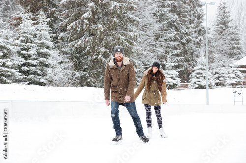 Fototapeta Smiling couple ice skating outdoors