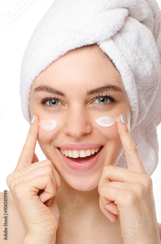 Beautiful young woman applying a creme on her face isolated on white background