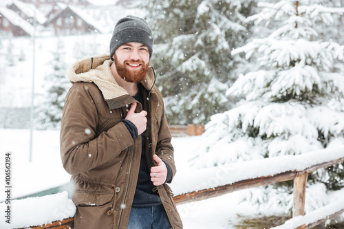 Happy bearded man standing in wintertime outdoors