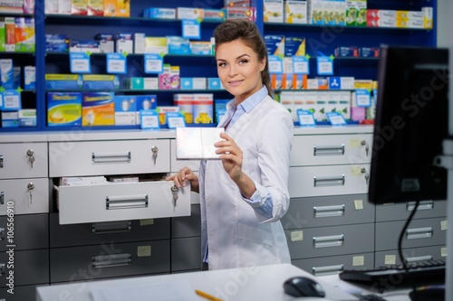Beautiful smiling young woman pharmacist doing his work in pharmacy.