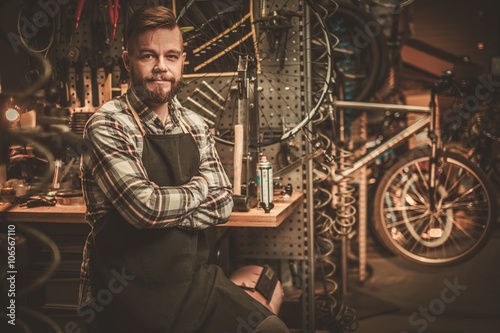 Stylish bicycle mechanic standing in his workshop.