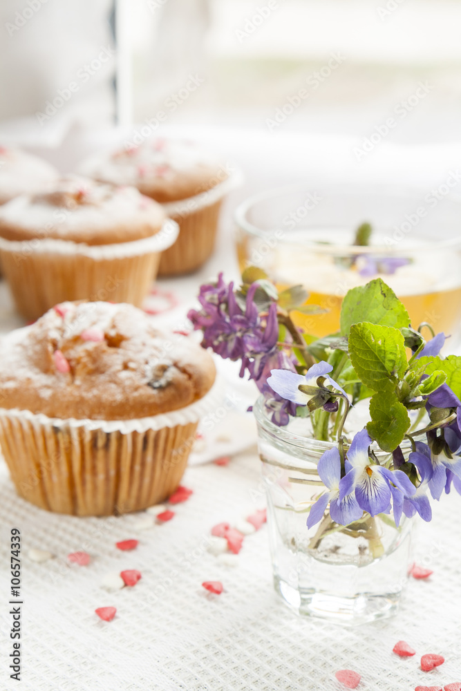 Blue spring flowers viola, muffins and cup of green tea Blue spring flowers viola, muffins and cup of green tea