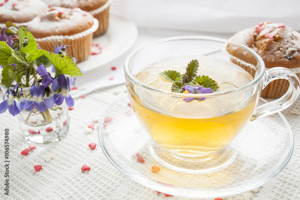 Cup of green tea with lemon balm and tasty muffins with sugar hearts Cup of green tea with lemon balm and tasty muffins with sugar hearts