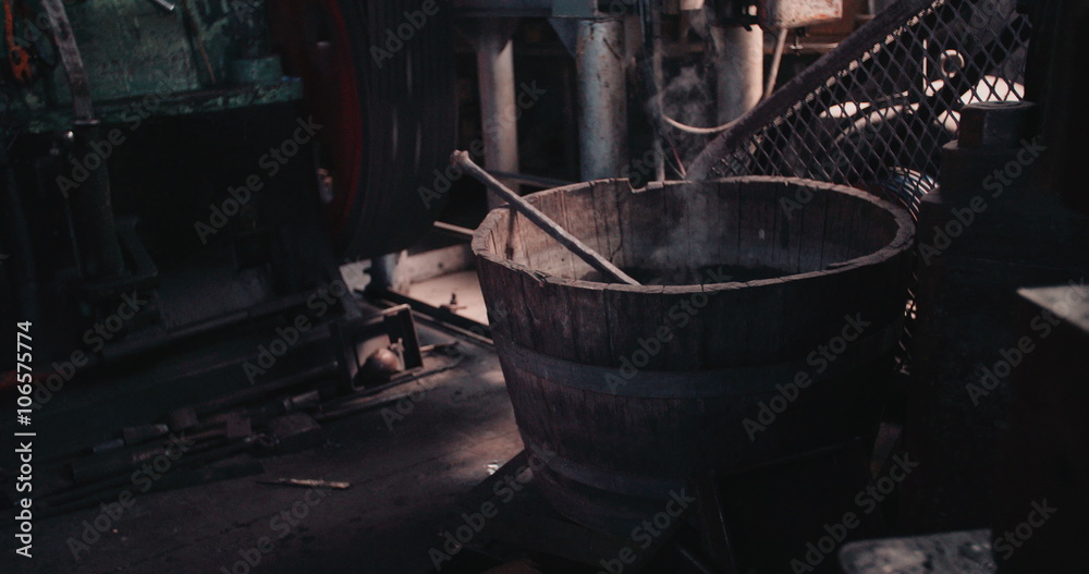 Steaming Iron cooling down in water barrel of blacksmith workshop Steaming Iron cooling down in water barrel of blacksmith workshop