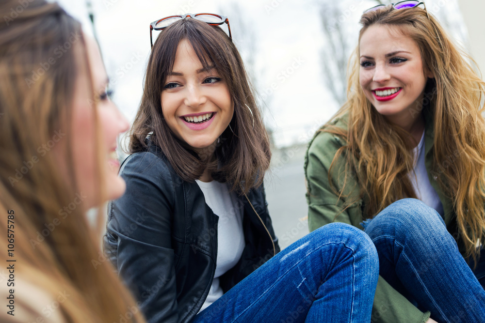 Three young women talking and laughing in the street.