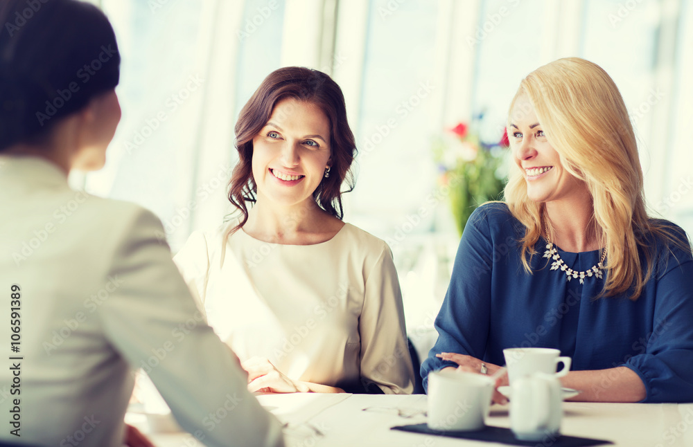 women drinking coffee and talking at restaurant women drinking coffee and talking at restaurant