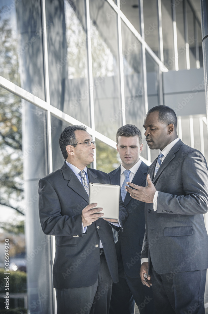 Businessmen using digital tablet outside office Businessmen using digital tablet outside office