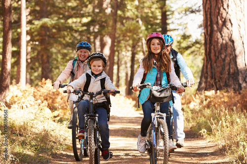 Grandparents and kids cycling on forest trail, California