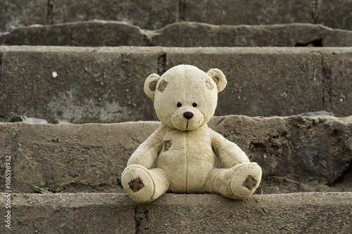 Teddy bear sits on the stone stairs.