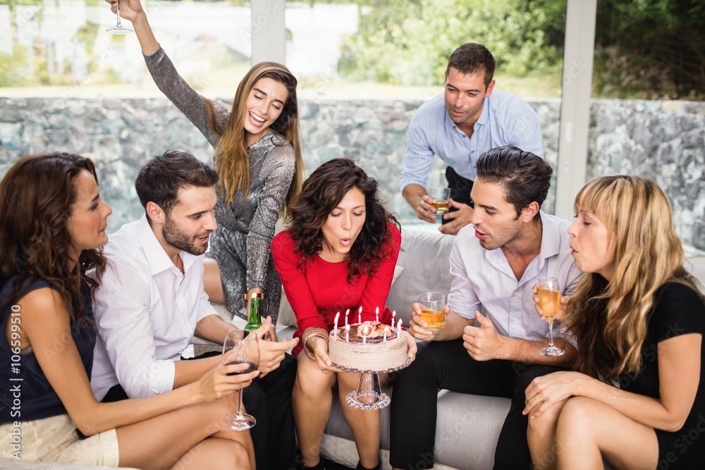 Woman blowing birthday candles with friends - obrazy, fototapety, plakaty 