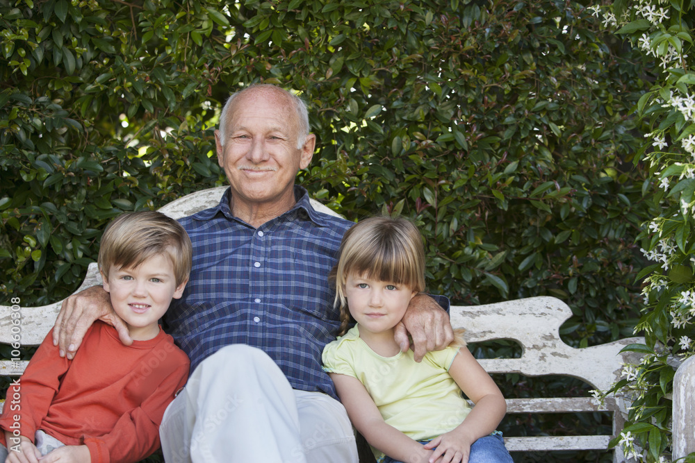 Grandfather sitting with grandchildren on garden bench Grandfather sitting with grandchildren on garden bench
