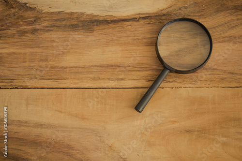 magnifying glass on the brown wooden background 