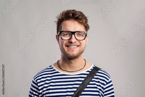 Man in striped t-shirt and eyeglasses against gray background. © Halfpoint