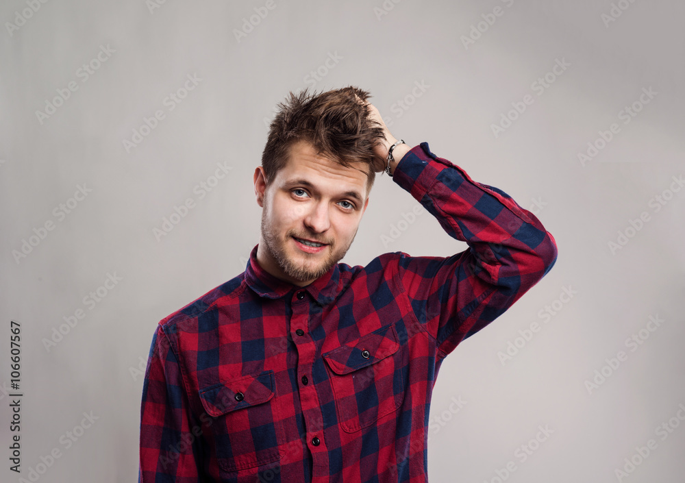 Hipster man in checked shirt smiling, against gray background. Hipster man in checked shirt smiling, against gray background.