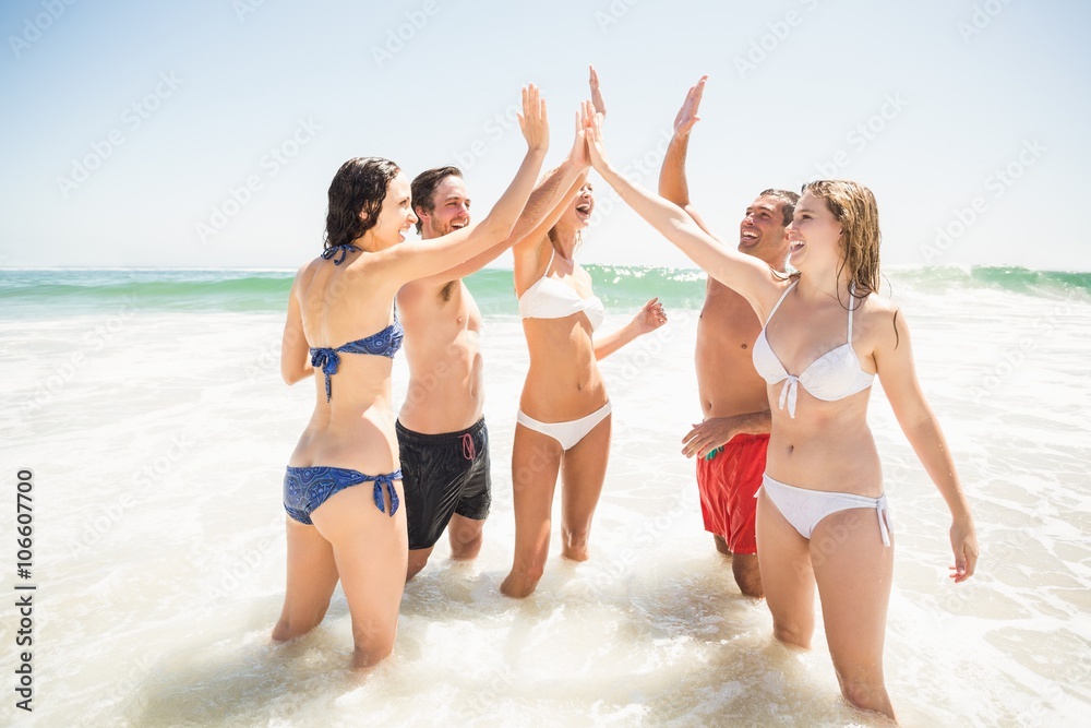 Happy friends giving a high five on the beach