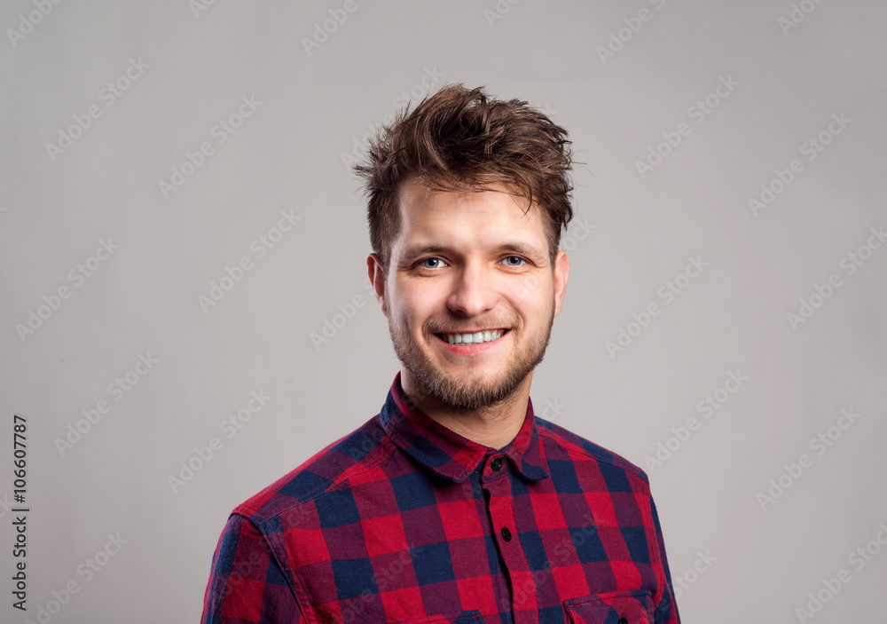 Hipster man in checked shirt smiling, against gray background. Hipster man in checked shirt smiling, against gray background.